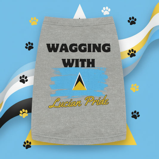 A dog wearing a gray tank top with 'WAGGING WITH LUCIAN PRIDE' printed on the front, featuring the St. Lucian flag.
